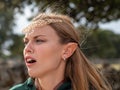 Close-up of blonde girl with blue eyes and elf ears wearing a green cape Royalty Free Stock Photo