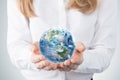 Close-up of blonde's hands who holds the globe with western hemisphere. A woman dressed in formal clothes.