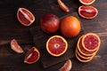 Close up of blood oranges whole, cut into slices and wedges on a dark wooden background, citrus fruit Royalty Free Stock Photo