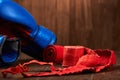 Close-up of the blue boxing gloves and red bandage on wooden background.