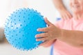 Blue, bumpy exercise ball held by a senior woman