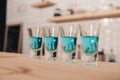 close up of blue cocktails in shot glasses standing on bar counter