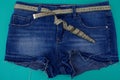 Close-up blue denim shorts with a centimeter instead of a belt on a blue background, next to an empty area.