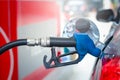 Close up of blue fuel petrol pump nozzle against for filling up the red car with petrol at gas station Royalty Free Stock Photo