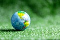Close up of blue globe on green grass on green blur nature background, earth day or world environment day concept. Green world and Royalty Free Stock Photo