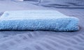 Close up of Blue inn linens and bath towel lying on bed. Hotel service and clean bedroom background. House room and home textile. Royalty Free Stock Photo