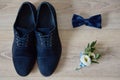 Close up of blue male shoes, bowtie and  boutonniere, copy space. Modern man accessories. Wedding details. Royalty Free Stock Photo