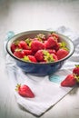 Close up of a blue metal bowl full of fresh strawberries over a white wood rustic background. Royalty Free Stock Photo