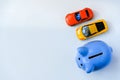 Piggy bank and two toy cars on white background with copy space
