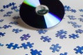 Close up of blue shattered puzzle pieces and DVD storage medium, white background Royalty Free Stock Photo