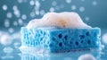 Close-up of blue sponge with foamy soap bubbles on wet surface, captured in vibrant lighting Royalty Free Stock Photo