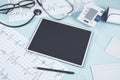 Close up of blue table with blank tablet, stethoscope, cardiogram, pen, other items and mock up place. Doctor`s office, workplace Royalty Free Stock Photo