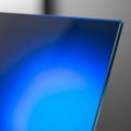 Close-up of a blue-tinted glass edge with a sharp, angular corner. The glass reflects ligh Royalty Free Stock Photo
