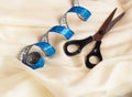 Close up of blue twisted tape measure and scissors on cream fabric with undulation Royalty Free Stock Photo