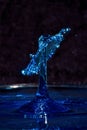 Close up of blue water drops colliding, creating a crown of water