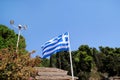 Close up of blue and white Greek flag on flagpole flying in the wind. Torn Greek national flag on old construction waving. Royalty Free Stock Photo