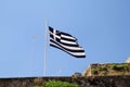 Close up of blue and white Greek flag on flagpole flying in the wind. Torn Greek national flag on old construction waving. Royalty Free Stock Photo