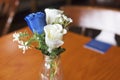 Close up of blue and white roses as a table decoration in a small glass vase at a traditional English wedding in the UK