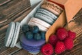 Close-up. Blueberries, raspberries and colored macaron cookies in a cardboard box on a wooden background