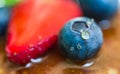 Close up of a blueberry with a drop of honey on the stack of pancakes.