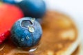 Close up of a blueberry with a drop of honey on the stack of pancakes.