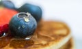 Close up of a blueberry with a drop of honey on the stack of pancakes.