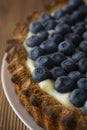 Close up blueberry tart or cake with cream and berries. Fresh sweet dessert with fruits. Homemade food, wooden, rustic background Royalty Free Stock Photo