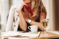 Close-up blur portrait of elegant woman wears red scarf and wristwatch with glass of wine on foreground. Blonde girl in Royalty Free Stock Photo