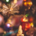 Close-up blurred fragment of Christmas tree with toys, lights of Gerland and tinsel. Retro toning style, focus out