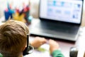 Selektive focus image.The boy learns with laptop at a distance remote learning,boy uses headphones with a microphone