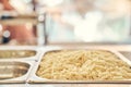 Close-up of boiled pasta, lying in a metal tray at the distribution in the hotel. A simple self-service concept.