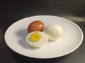 Close up boliled eggs. boiled egg in half, whole egg and brown egg in a white plate Royalty Free Stock Photo