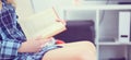 Close - up of a book in the hands of a girl sitting on the couch on home interior background Royalty Free Stock Photo