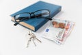 Close up of book, money, glasses and keys on table