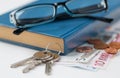 Close up of book, money, glasses and keys on table