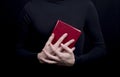 close-up of a book in the red cover in the hands of a man in black clothes Royalty Free Stock Photo