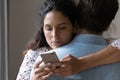 Young woman hug husband cheating online on cellphone