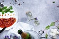 Close-up of a bottle of champagne, white plate with canned beans, garlic, almond, tomatoes on a light background.