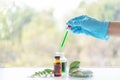 Close up bottle of essential oils with scientist holding dropper. Lab research for scent extract for the new skincare product