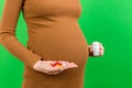 Close up of a bottle and heap of pills in pregnant woman`s hands at colorful background with copy space. Healthy pregnancy concep