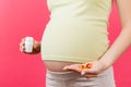 Close up of a bottle and heap of pills in pregnant woman`s hands at colorful background with copy space. Healthy pregnancy concep