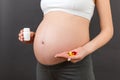 Close up of a bottle and heap of pills in pregnant woman`s hands at colorful background with copy space. Healthy pregnancy concep