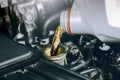 Close up of a bottle of motor oil being poured into a car combustion engine for lubricate. Oil change in car engine