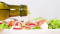 Close-up of a bottle pouring olive oil into a vegetable salad Royalty Free Stock Photo