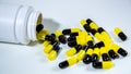 Close up on a bottle of prescription drugs falling out. Black and yellow pills Royalty Free Stock Photo