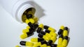 Close up on a bottle of prescription drugs falling out. Black and yellow pills Royalty Free Stock Photo