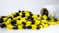 Close up on a bottle of prescription drugs falling out. Black and yellow pills Royalty Free Stock Photo