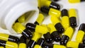 Close up on a bottle of prescription drugs falling out. Black and yellow pills Royalty Free Stock Photo