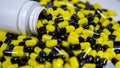 Close up on a bottle of prescription drugs falling out. Black and yellow pills Royalty Free Stock Photo