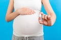 Close up of a bottle of vitamin pills in pregnant woman`s hand at colorful background with copy space. Healthcare concept